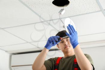 Electrician installing lamp on ceiling�