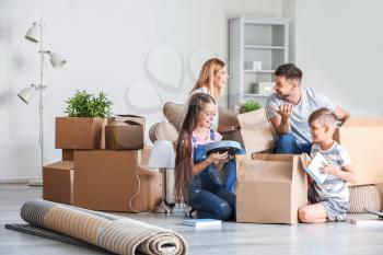 Happy family unpacking belongings in their new house�