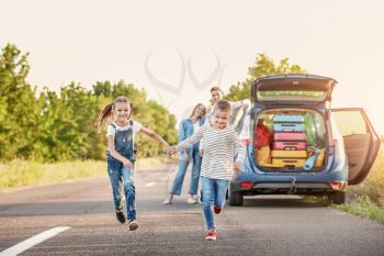 Happy children and their parents near car outdoors�