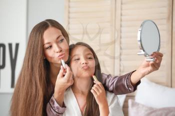 Mother with daughter doing makeup at home in morning�