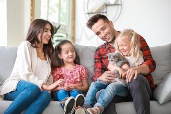 Happy family with cute cat resting at home�