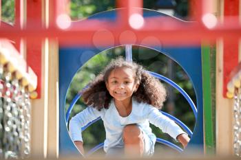 Cute African-American girl having fun on playground outdoors�