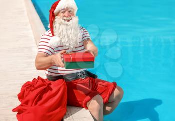 Santa Claus with gift near swimming pool at resort�