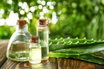 Bottles of aloe vera essential oil on wooden table�