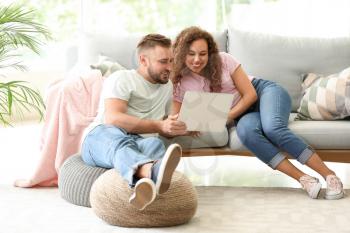 Happy young couple with laptop relaxing at home�