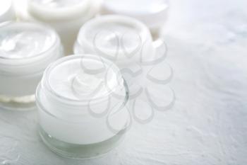Jars of body cream on white table�