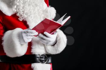 Santa Claus with book on dark background, closeup�
