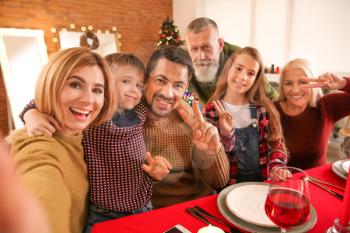 Happy family taking selfie during Christmas dinner at home�