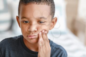 Little African-American boy suffering from toothache at home�