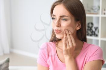 Young woman suffering from toothache at home�