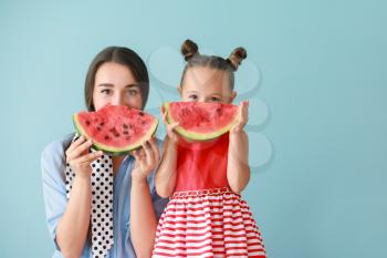 Beautiful young woman and cute little girl with fresh watermelon on color background�