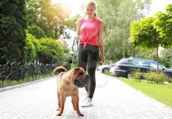 Sporty woman with cute dog walking outdoors�