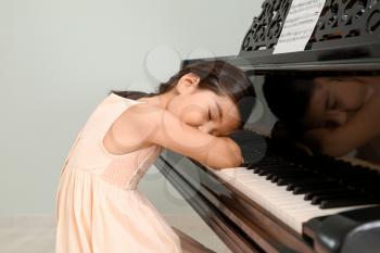 Little girl sleeping at grand piano�