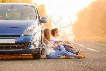 Happy couple near their new car sitting on road in countryside�
