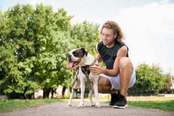 Sporty young man with cute dog in park�