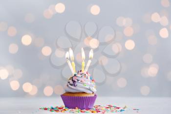 Tasty Birthday cupcake on table against defocused lights�
