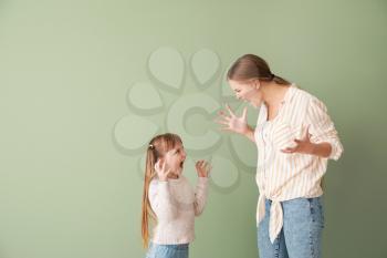Portrait of quarrelling mother and little daughter on color background�