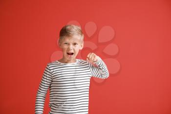 Portrait of angry little boy on color background�