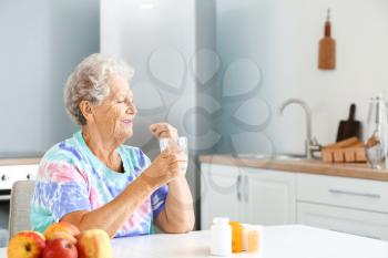 Elderly woman taking medicine at home�