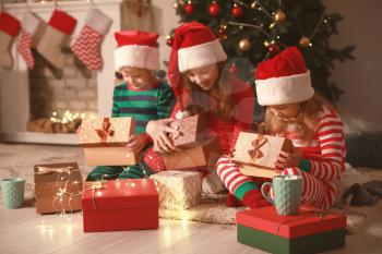 Cute little children opening Christmas gifts at home�