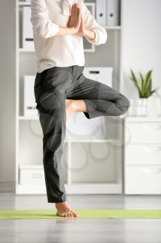 Young businesswoman practicing yoga in office�