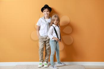 Stylish little children near color wall�
