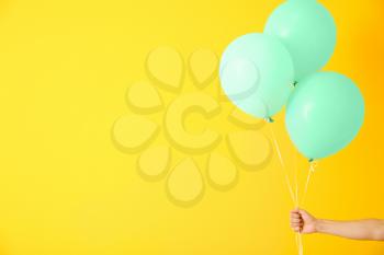 Female hand with air balloons on color background�