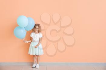 Little girl with balloons near color wall�