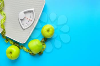 Scales, apples and measuring tape on color background. Weight loss concept�