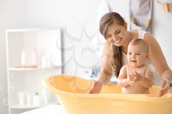 Mother bathing her cute little baby at home�