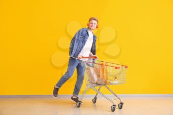 Young man with shopping cart near color wall�