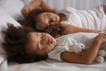Little African-American girl with mother sleeping in bed at night�