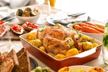 Baking dish with tasty chicken and potato on served table�