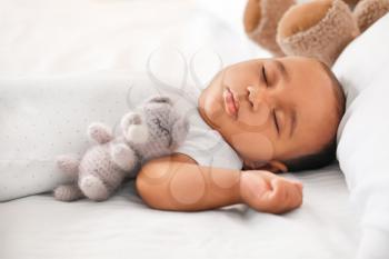 Cute African-American baby sleeping on bed�