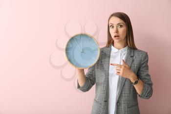 Young businesswoman with clock on color background�