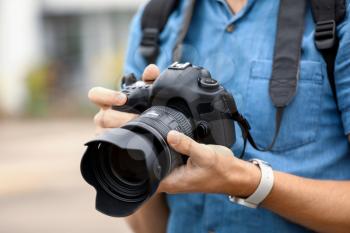 Young male photographer with camera outdoors, closeup�