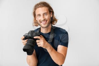 Young male photographer on light background�