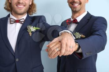 Happy gay couple on their wedding day against color background�