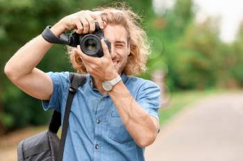 Young male photographer with camera outdoors�