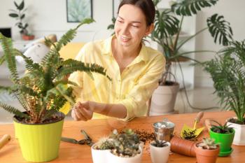 Young woman taking care for houseplants at home�