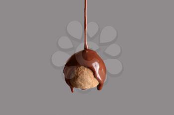 Pouring of chocolate on truffle candy against grey background�