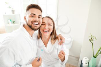 Young couple brushing teeth in bathroom�