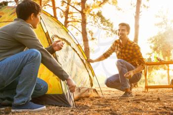 Friends putting up camping tent in forest�