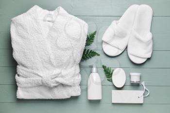 Clean bathrobe with spa supplies on wooden background�