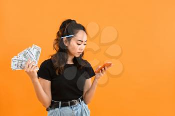 Sad Asian woman with money and calculator on color background�