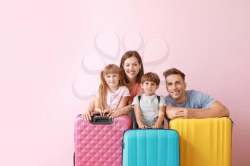 Happy family with luggage on color background�