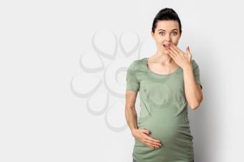 Beautiful surprised pregnant woman on light background�