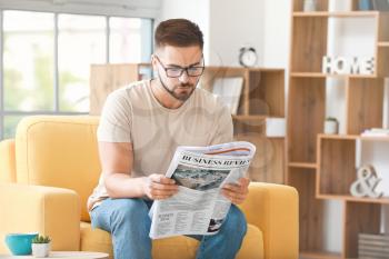 Handsome man reading newspaper at home�