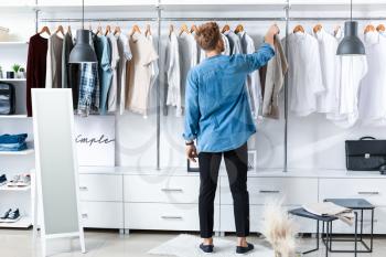 Handsome man choosing clothes in dressing room�