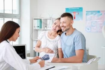 Pregnant couple visiting female gynecologist in clinic�